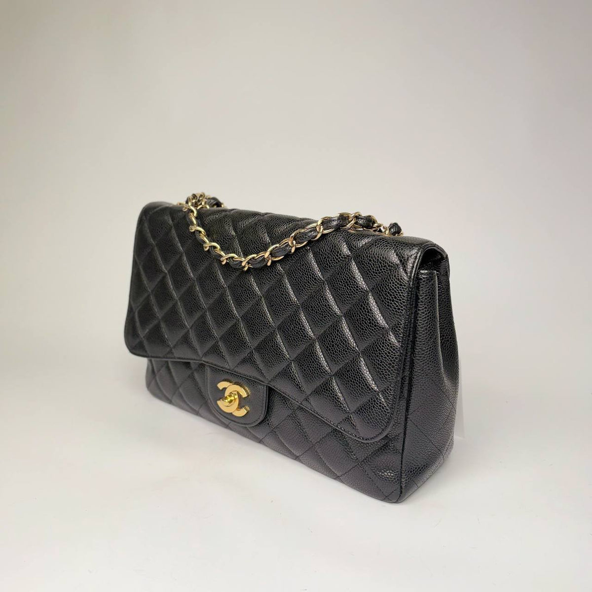 Chanel Jumbo Single Flap Bag black caviar, angled side view with leather-woven chain
