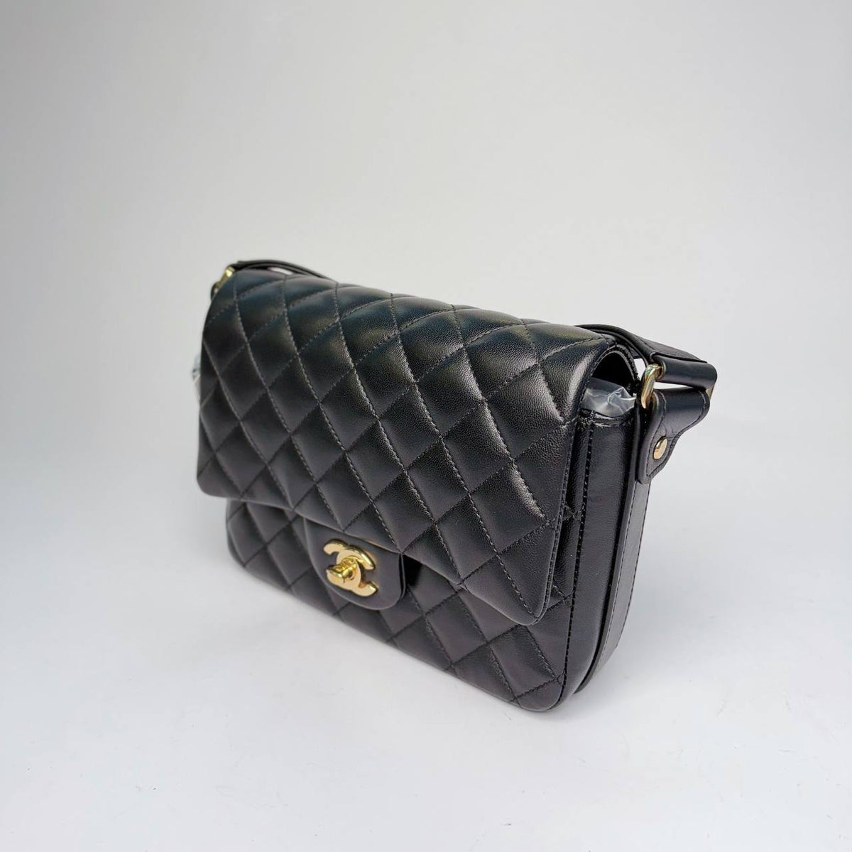 Chanel quilted flap bag black, angled side view of the leather shoulder strap
