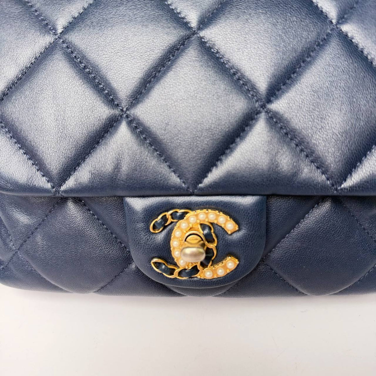 Chanel mini flap bag navy, close-up of the CC turnlock set with pearls and woven chain