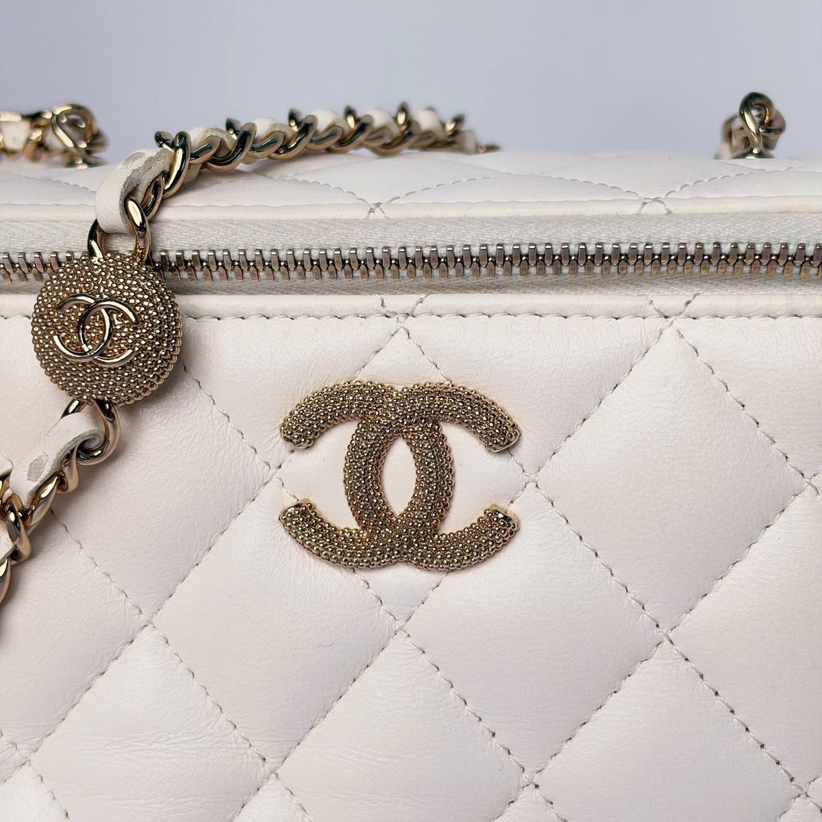 Chanel Vanity Case white leather, close-up of textured CC and ball chain slider