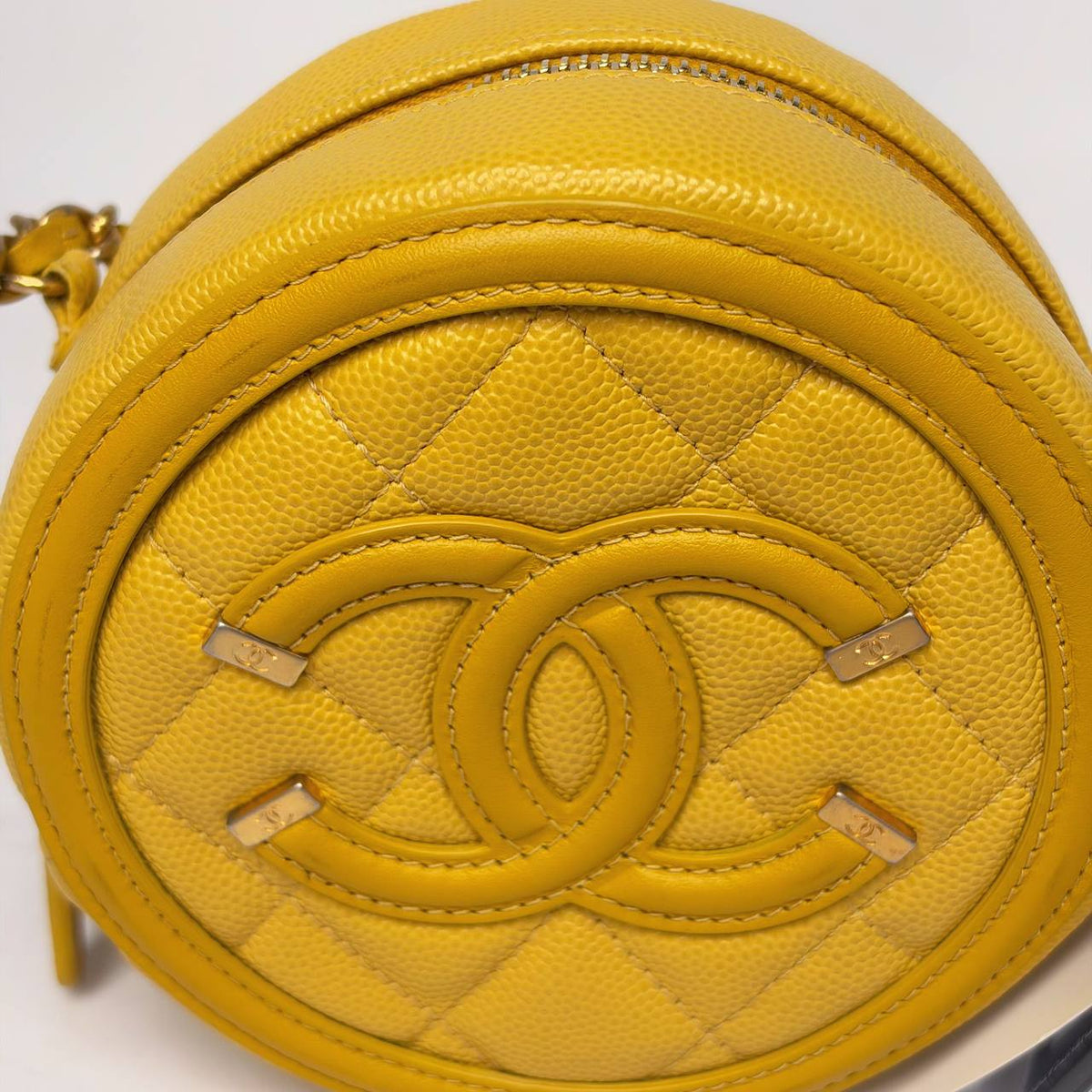 Chanel Filigree Round Clutch yellow, close-up of the stitched CC logo with gold filigree accents
