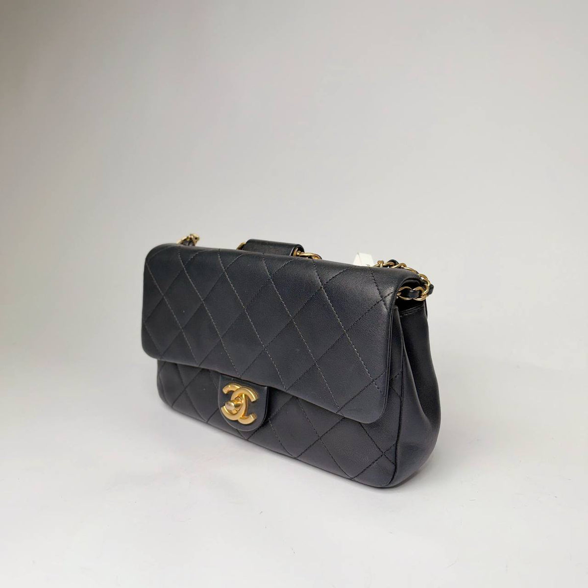 Chanel quilted flap bag black lambskin, angled side view with chain