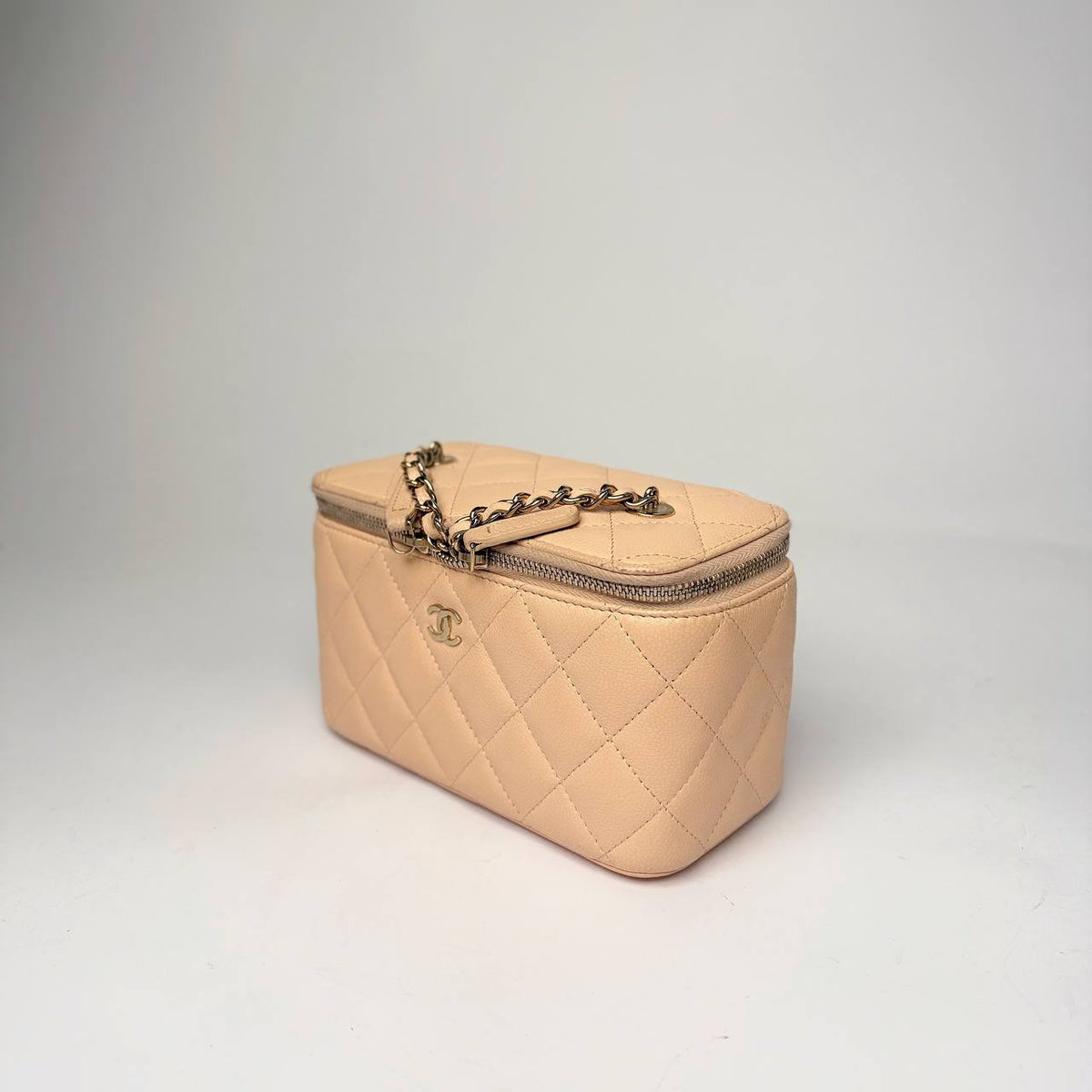 Chanel Small Vanity Case light beige caviar, three-quarter side view with leather-woven chain