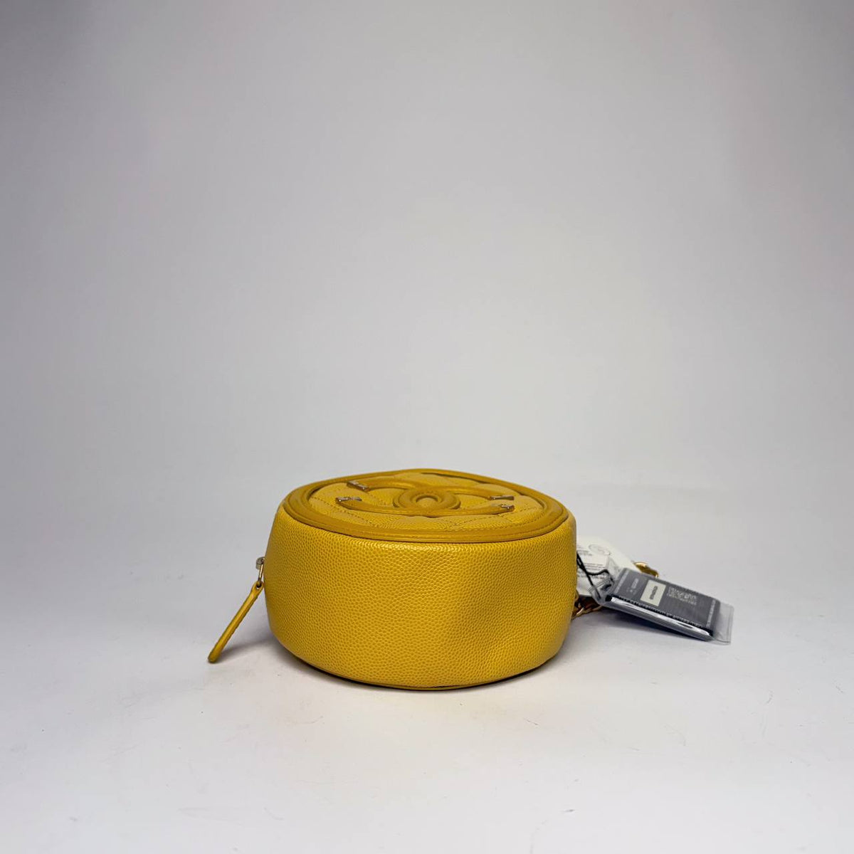 Chanel Filigree Round Clutch yellow caviar, side profile with zipper pull