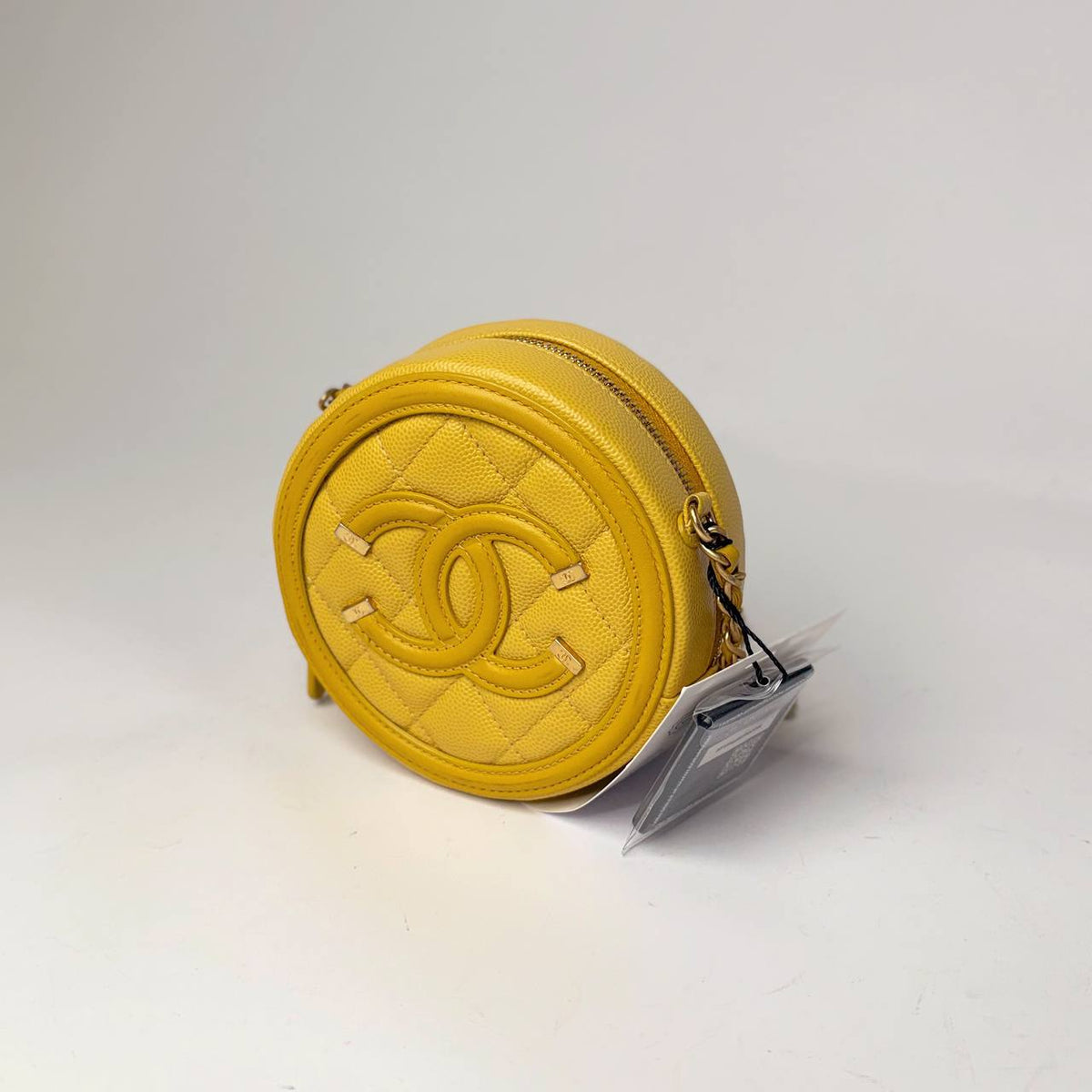 Chanel Filigree Round Clutch yellow caviar, three-quarter view showing the zip-around top