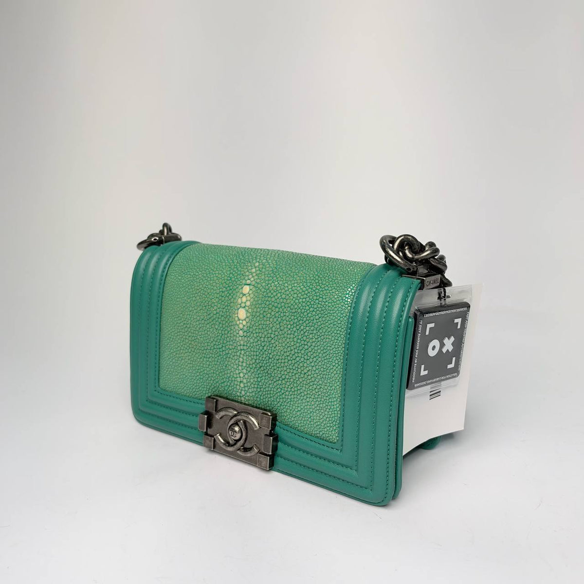 Chanel Boy Bag turquoise galuchat, three-quarter side view with chain strap and hang tag