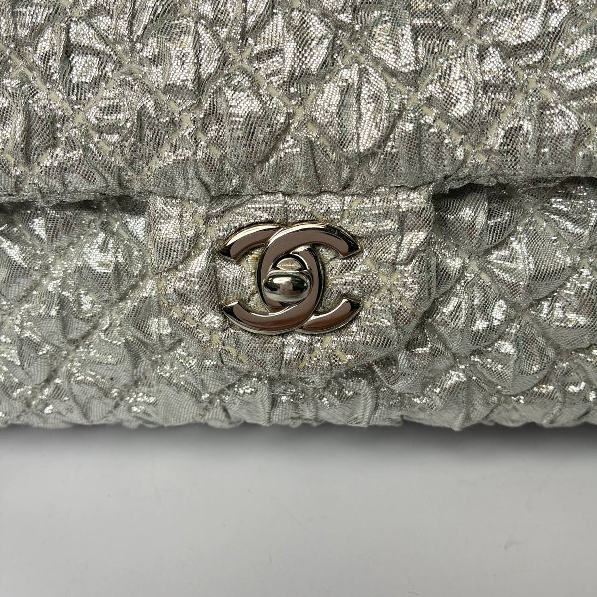 Chanel Classic Flap Bag silver metallic, close-up of CC turnlock and woven texture
