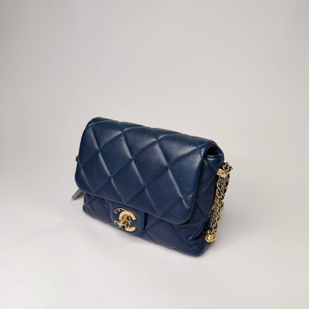 Chanel mini flap bag navy lambskin, three-quarter side view with leather-woven chain