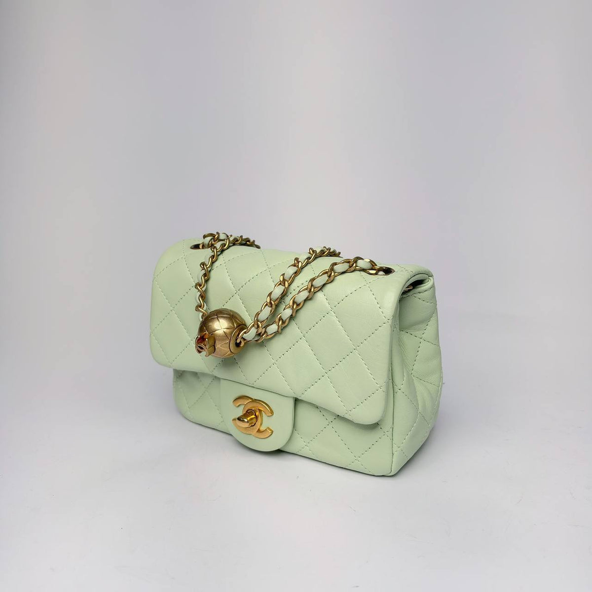 Chanel Pearl Crush Mini Flap Bag light green, three-quarter view with gold ball on the chain