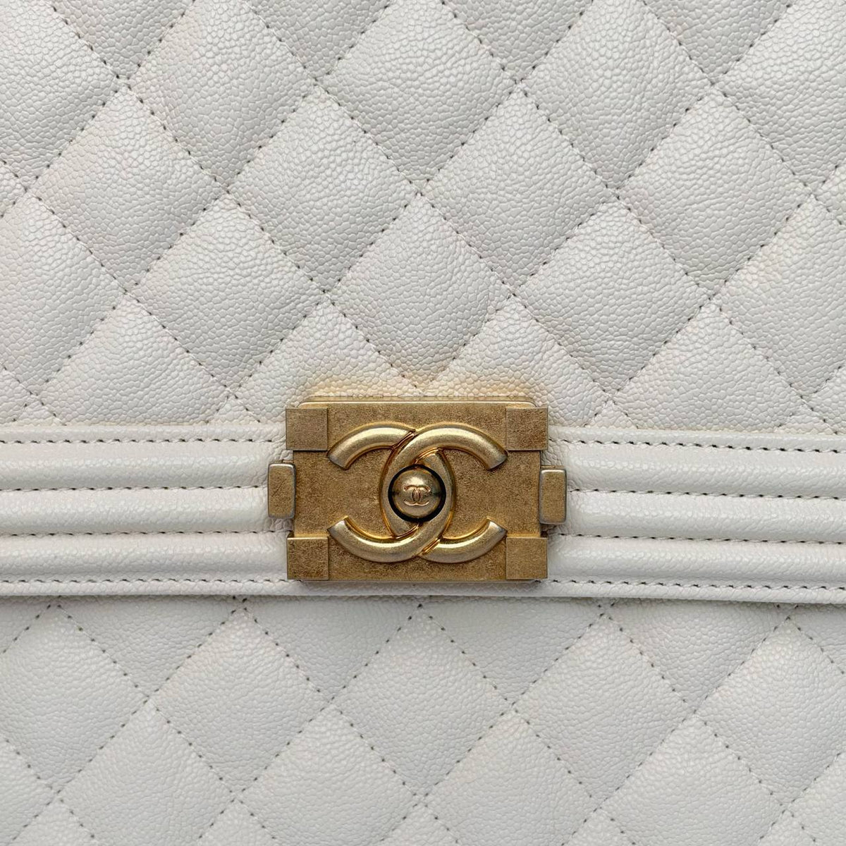Chanel North South Boy Bag white, close-up of the gold Boy clasp and caviar grain