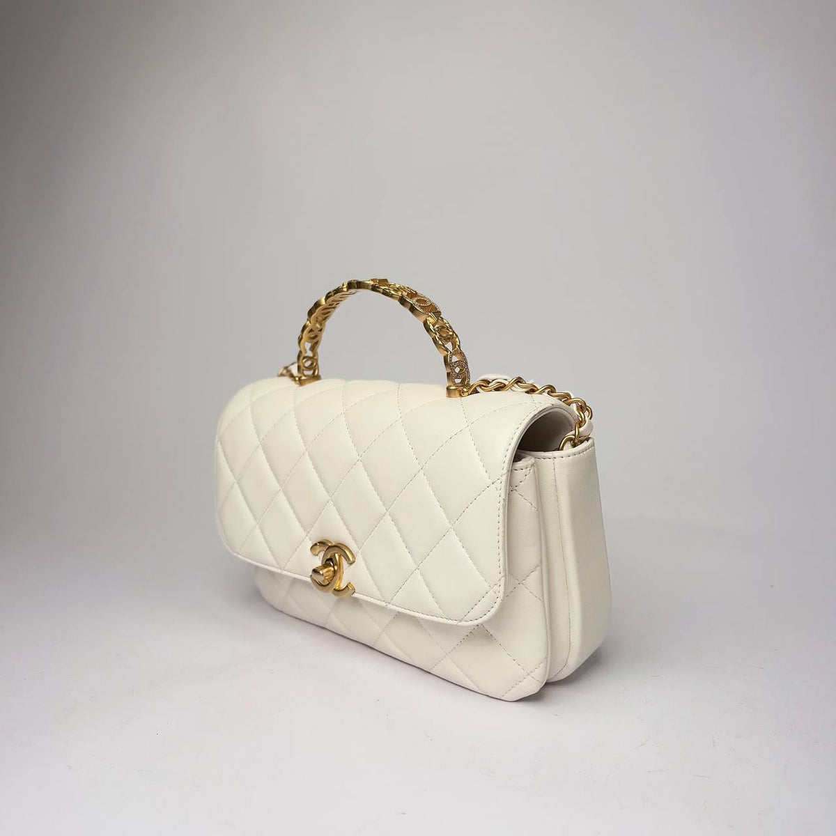 Chanel Small Top Handle Flap Bag white lambskin, three-quarter view of the crystal-set CC link handle